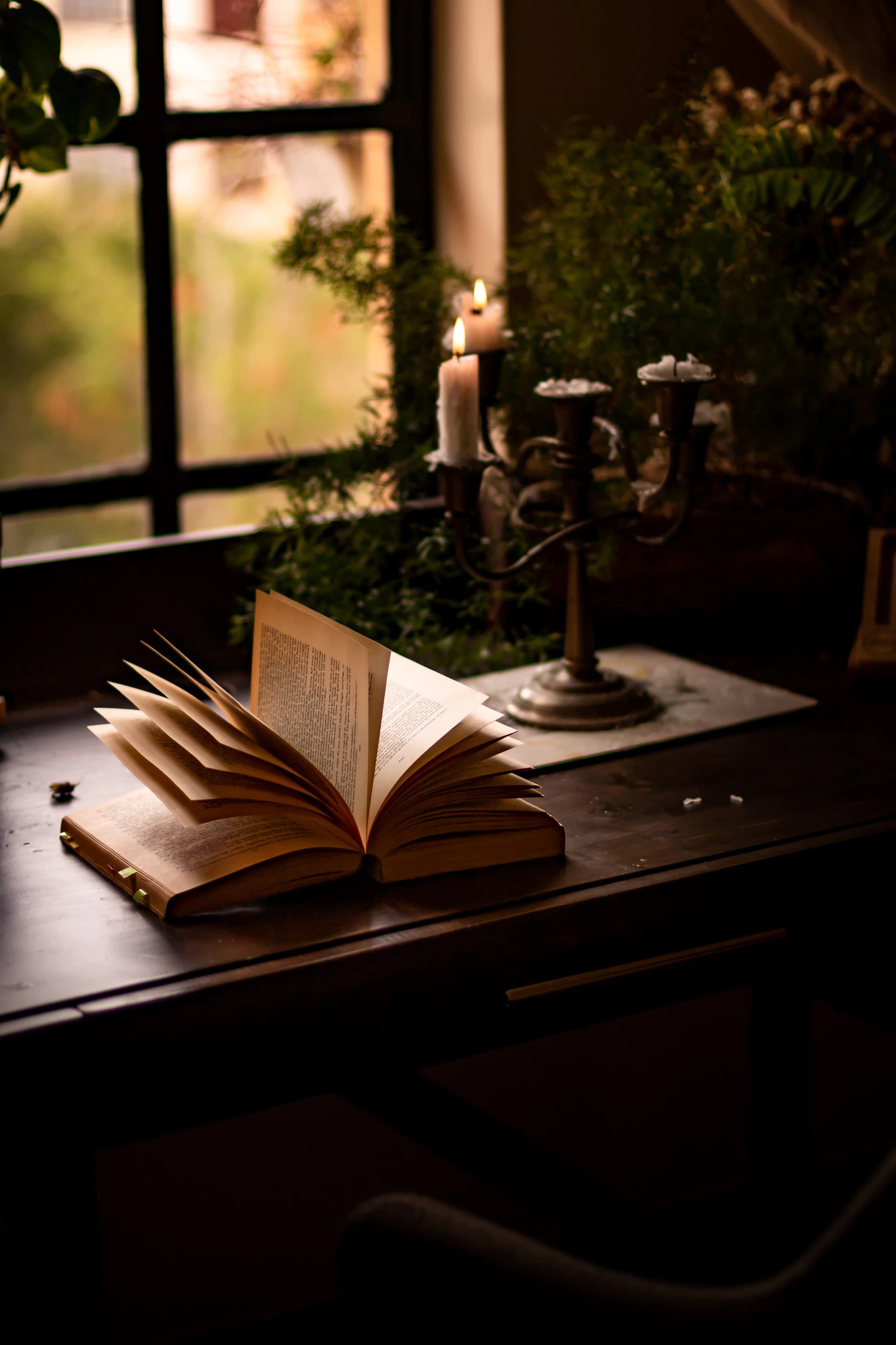 A candle on a stack of books near a window