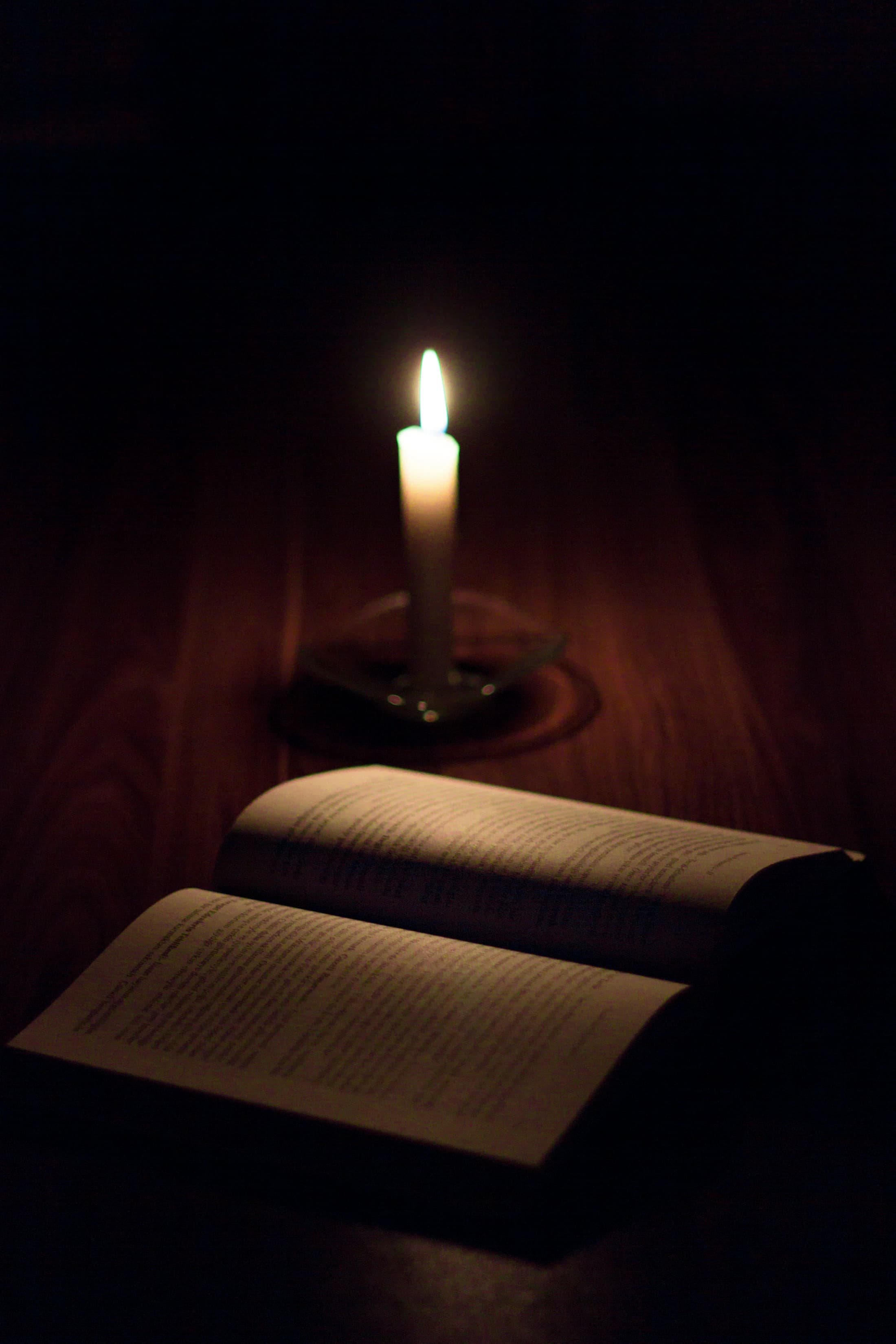 A pillar candle illuminating the pages of a book
